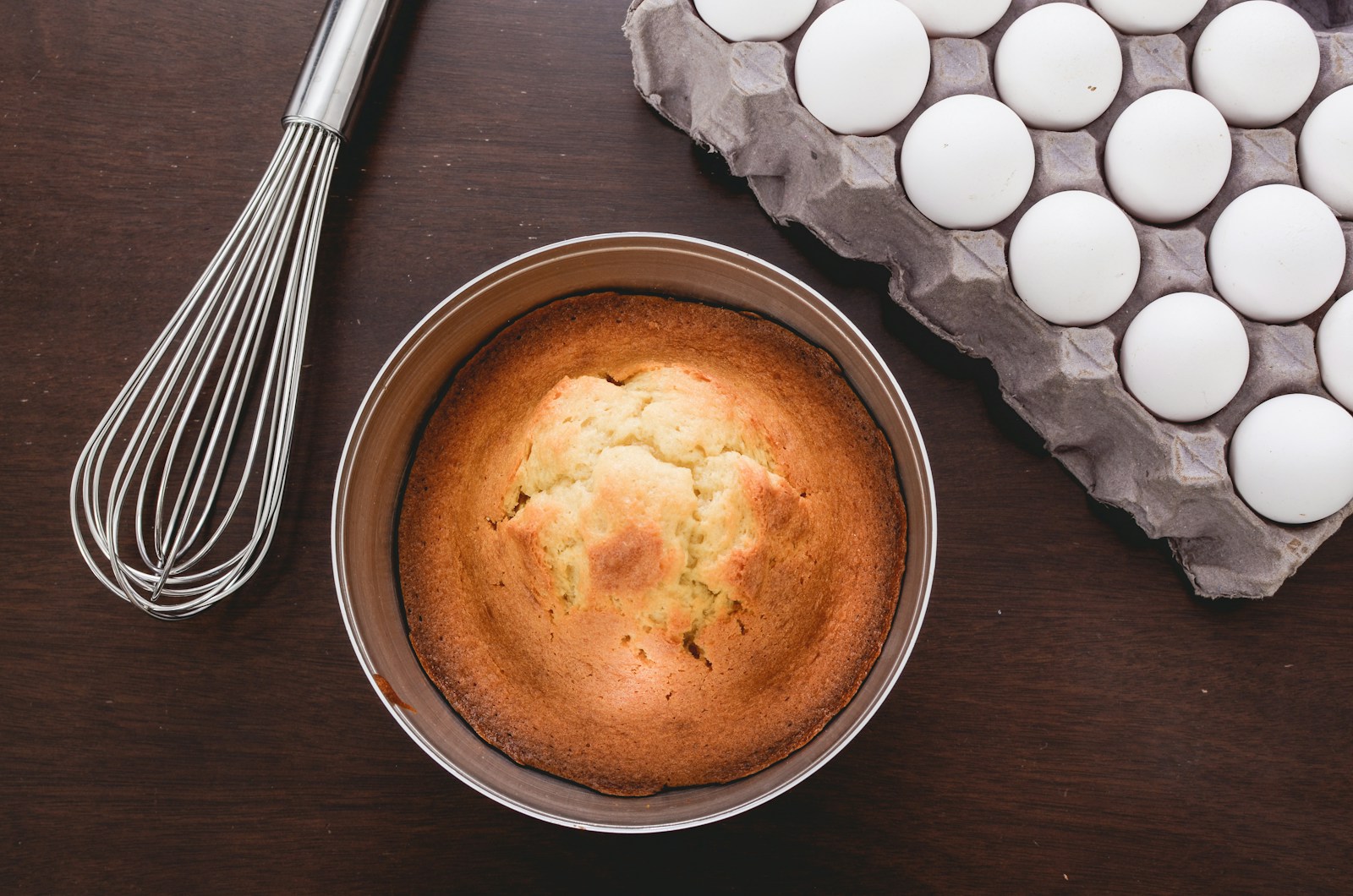 baked muffins beside tray of eggs and whisker
