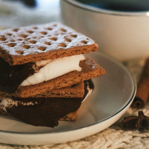a stack of waffle sandwiches on a plate next to a cup of coffee