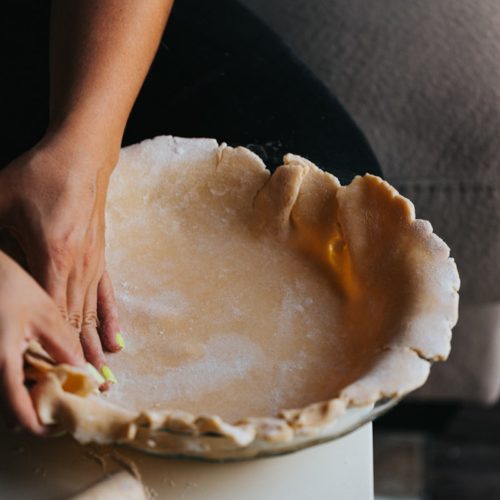 person holding white ceramic bowl with brown and white cake