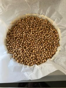 Fond de tarte recouvert d’une feuille de papier sulfurisé puis d’une couche de pois-chiche secs, prêt à enfourner